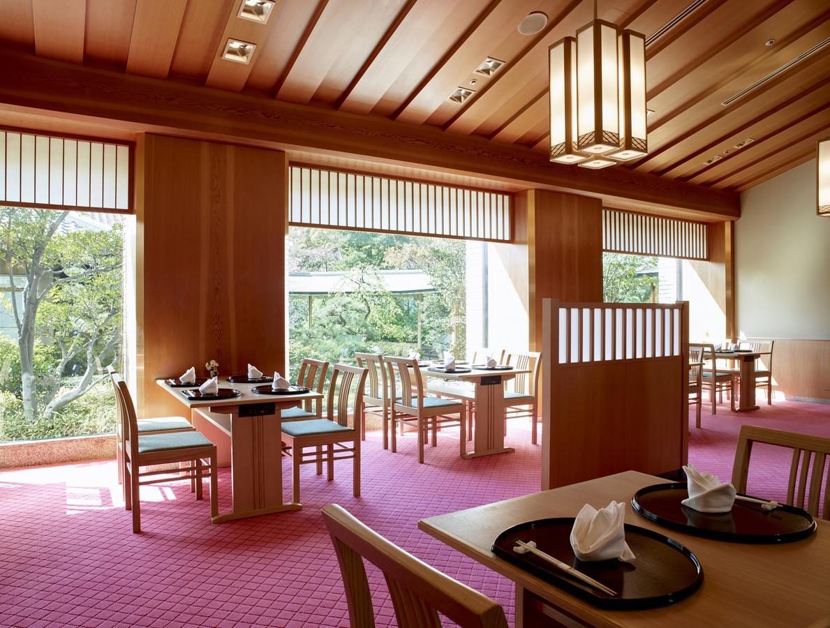 Hotel Okura Kōbe Exterior foto The photo depicts an elegantly designed restaurant interior. It features wooden paneling and a slanted wooden ceiling that adds warmth to the space. The flooring is covered with a soft pink carpet, creating a cozy atmosphere. 

There are several wood